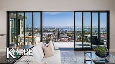 a living room filled with furniture next to a large window covered in glass and overlooking the city