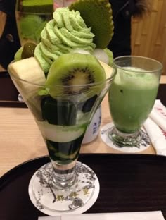 two glasses filled with different types of food on a tray next to each other and one has a slice of kiwi in it