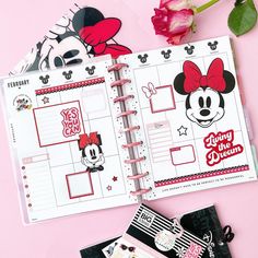 an open mickey mouse planner next to a pink rose