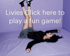 a woman laying on top of a bed with her legs up in the air while playing a game