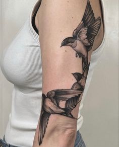 a woman with a black and white tattoo on her arm holding a bird in the air