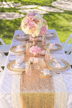 the table is set with gold and white plates, silverware and flowers on it