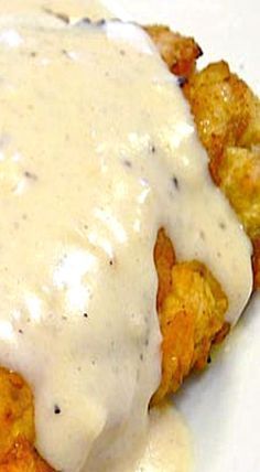 a white plate topped with fried chicken covered in gravy and ranch dressing on top of it