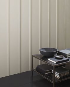 a black bowl sitting on top of a glass table next to a book shelf and window