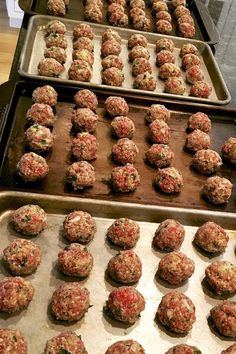 several trays of meatballs are lined up and ready to go into the oven