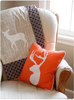 an orange and white pillow sitting on top of a chair next to a deer head