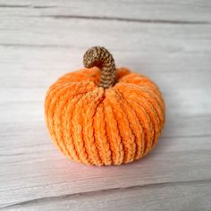 an orange yarn pumpkin sitting on top of a wooden table