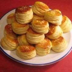 a white plate topped with lots of small pastries on top of a red table