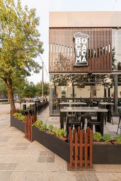 an outdoor dining area with tables and chairs in front of a building on the sidewalk