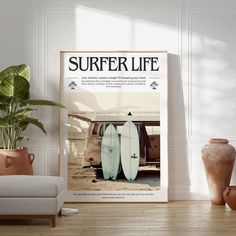 there is a poster with two surfboards in front of a couch and potted plant