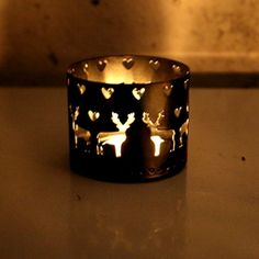 a lit candle holder with deer and hearts on the inside, sitting on a table