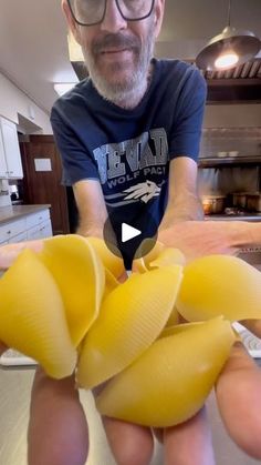 a man is holding some yellow noodles in his hand while he looks at the camera