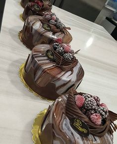 three chocolate cakes with raspberries and other toppings sitting on top of a counter