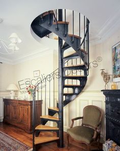 there is a spiral staircase in the living room with two chairs and a dresser next to it