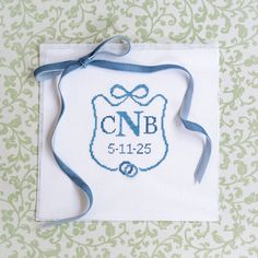 a cross stitched badge with a blue ribbon hanging from it's side on a green and white wall