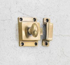 an old brass door handle on a white marble surface with two black knobs and one is missing