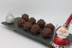 a santa clause figurine holding a knife next to chocolate truffles