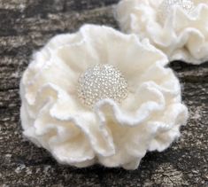 two white flower brooches sitting on top of a rock