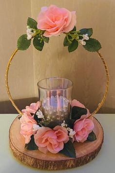 a vase with pink flowers and greenery on top of a wooden slice in front of a wall