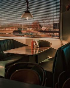 an empty restaurant table with chairs and a lamp hanging over it's head in front of a window