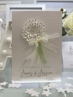 congratulations card with white flowers and ribbon on display in front of other greetings cards