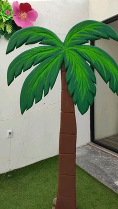 a cardboard palm tree sitting on top of green grass