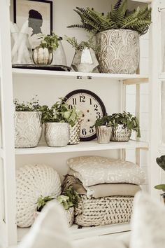 a shelf filled with lots of plants and pots on top of each other in front of a clock