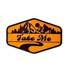 an orange and black sticker with the words take me in front of some mountains