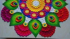 an intricately designed rang art work with colorful flowers and leaves on white paper, ready to be made into a wall hanging