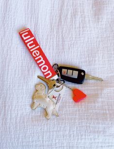 there is a keychain and two keys on top of a white bed sheet