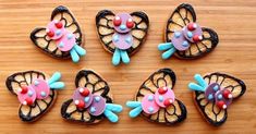 six butterfly shaped cookies sitting on top of a wooden table with frosting and sprinkles