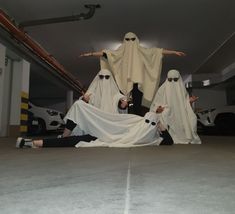 three people dressed up in ghost costumes sitting on the ground