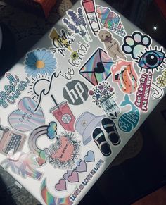 a laptop covered in stickers sitting on top of a table