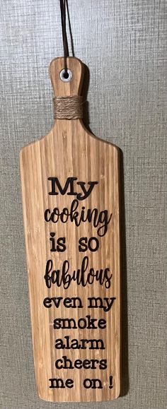 a wooden cutting board hanging on the wall with words written in black and white ink