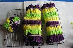 purple, yellow and green cakes sitting on top of a cooling rack next to yarn