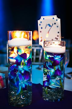 two vases with flowers and candles on a table