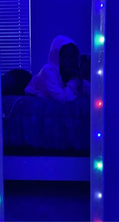 a person sitting in a bed with lights on the sides of it and their head turned to the side