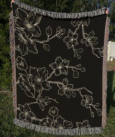 a large black and white flowered blanket hanging from a clothes line in the grass