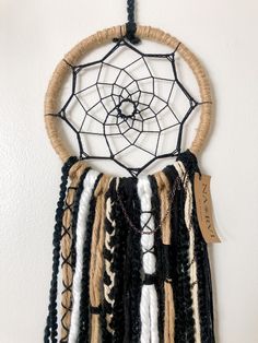 a black and white dream catcher hanging on the wall