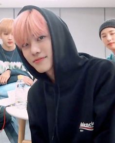 group of young men sitting around a table with one man wearing a black hoodie