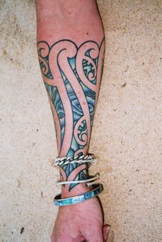 a person's arm with tattoos on it and bracelets attached to the wrist