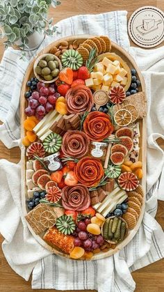 a platter filled with fruit and crackers on top of a white towel next to a potted plant