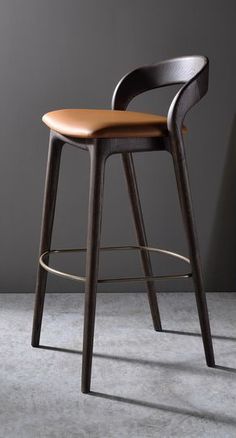 a bar stool with a brown leather seat and back rests in front of a bookcase