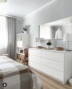 a bed room with a neatly made bed next to a dresser and mirror on the wall