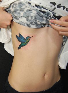 a woman's stomach with a hummingbird tattoo on it