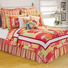 the bed is covered with colorful comforters and pillows