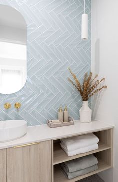 a white sink sitting under a bathroom mirror next to a wooden shelf with towels on it