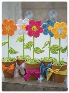 crocheted flowers in small pots with bows on the stems and ribbons tied around them