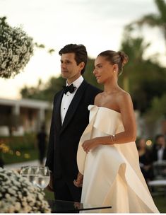 a man in a tuxedo standing next to a woman in a white dress