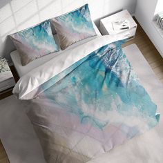 a bed with blue and white paint on the sheets, pillows and pillow cases in a room